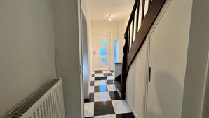 A hallway with a checkered floor, a radiator, and a staircase with wooden railings.