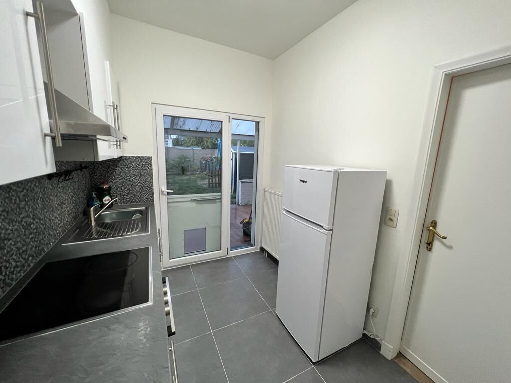 A compact kitchen with a built-in oven, a refrigerator, and a sliding glass door leading to a patio.