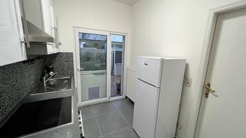 A compact kitchen with a built-in oven, a refrigerator, and a sliding glass door leading to a patio.