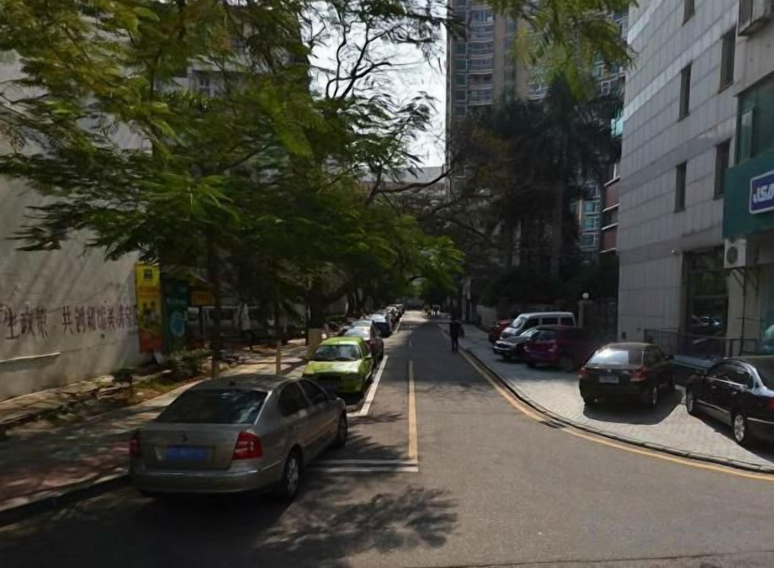 A street with parked cars and buildings on both sides.