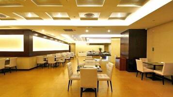 A hotel lobby with a reception desk, multiple seating areas, and a bar.
