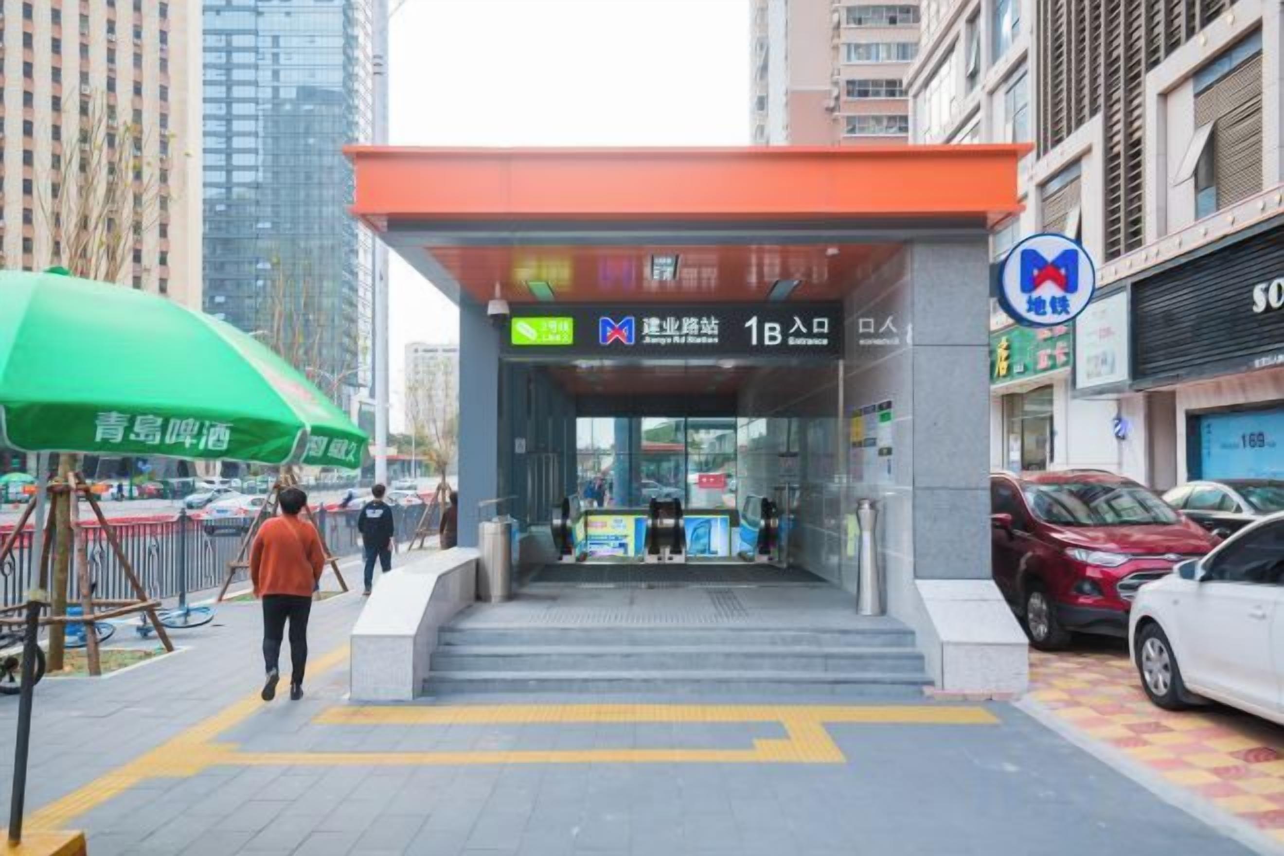 A building entrance with a sign indicating a 1B room and a green umbrella.