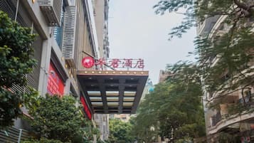 A narrow street with a building featuring a prominent red sign.