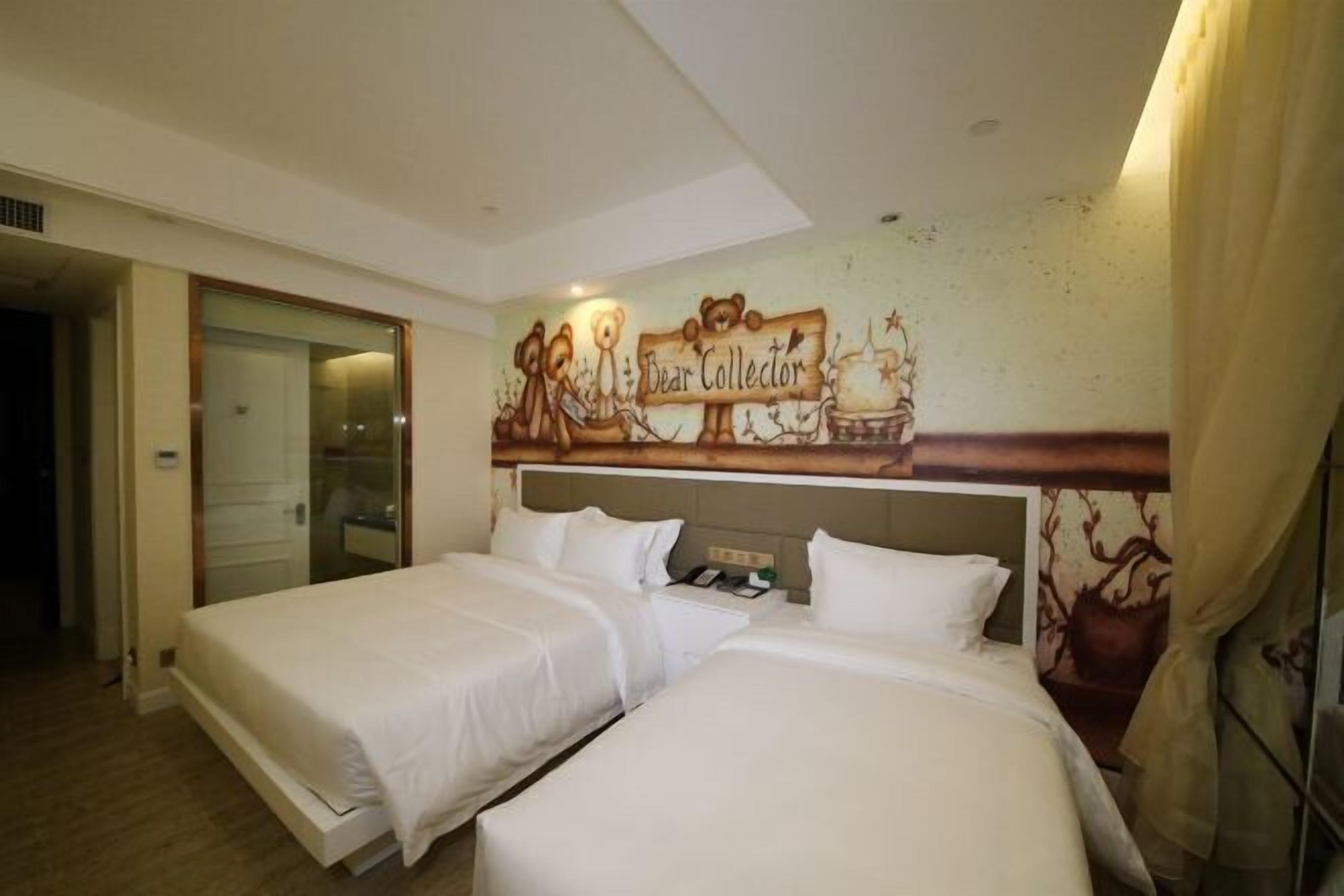 Quarto de hotel com duas camas, um mural grande na parede e uma porta para o banheiro.