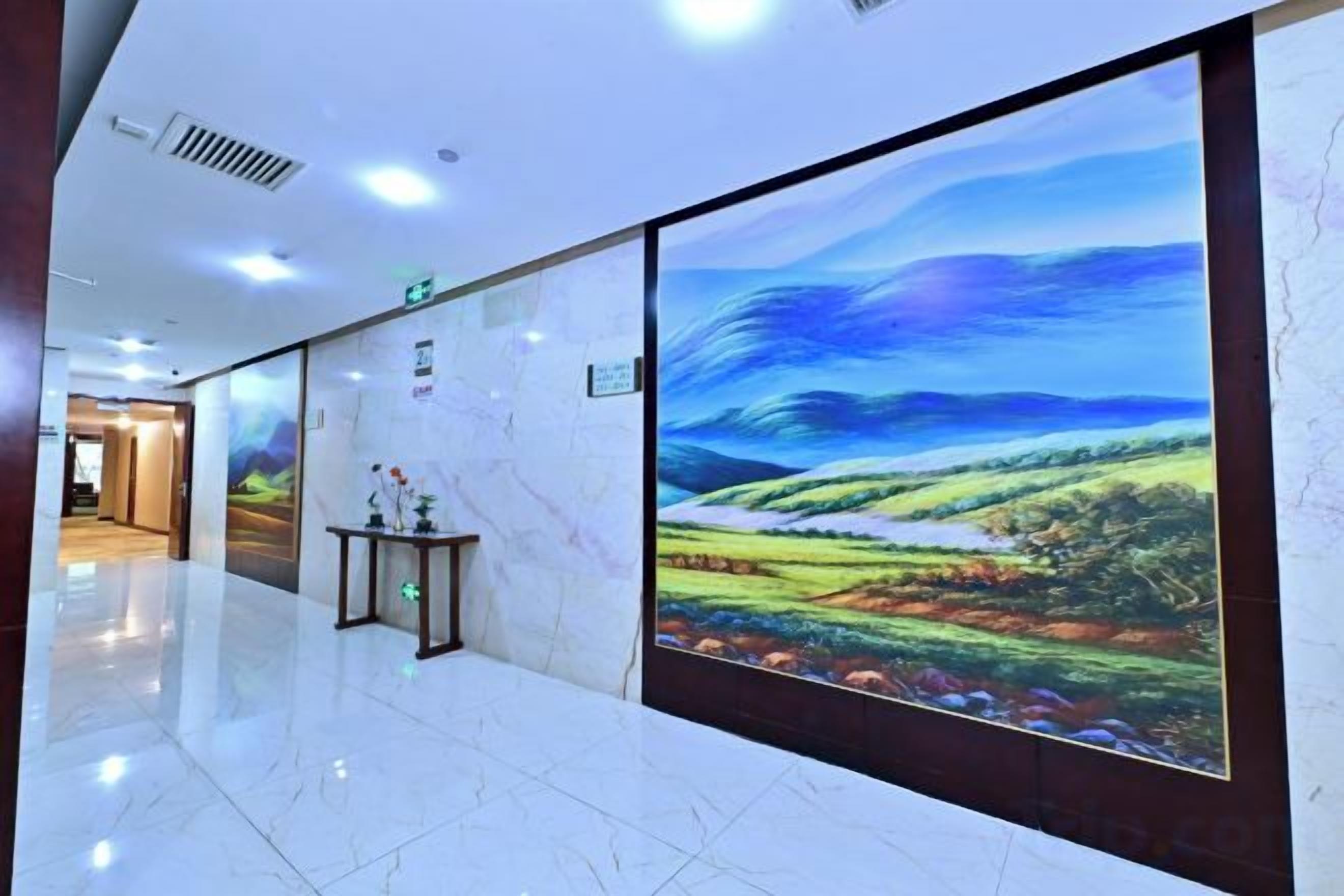 Un pasillo con un gran mural digital de paisaje, suelo de mármol y un mostrador de recepción.