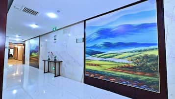 Un pasillo con un gran mural digital de paisaje, suelo de mármol y un mostrador de recepción.