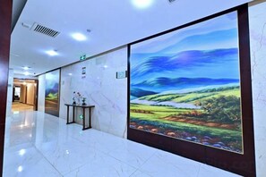 Un pasillo con un gran mural digital de paisaje, suelo de mármol y un mostrador de recepción.