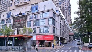 A multi-story building with a ground-level commercial space, including a restaurant with a red awning. - Huajun Hotel (Xiamen)