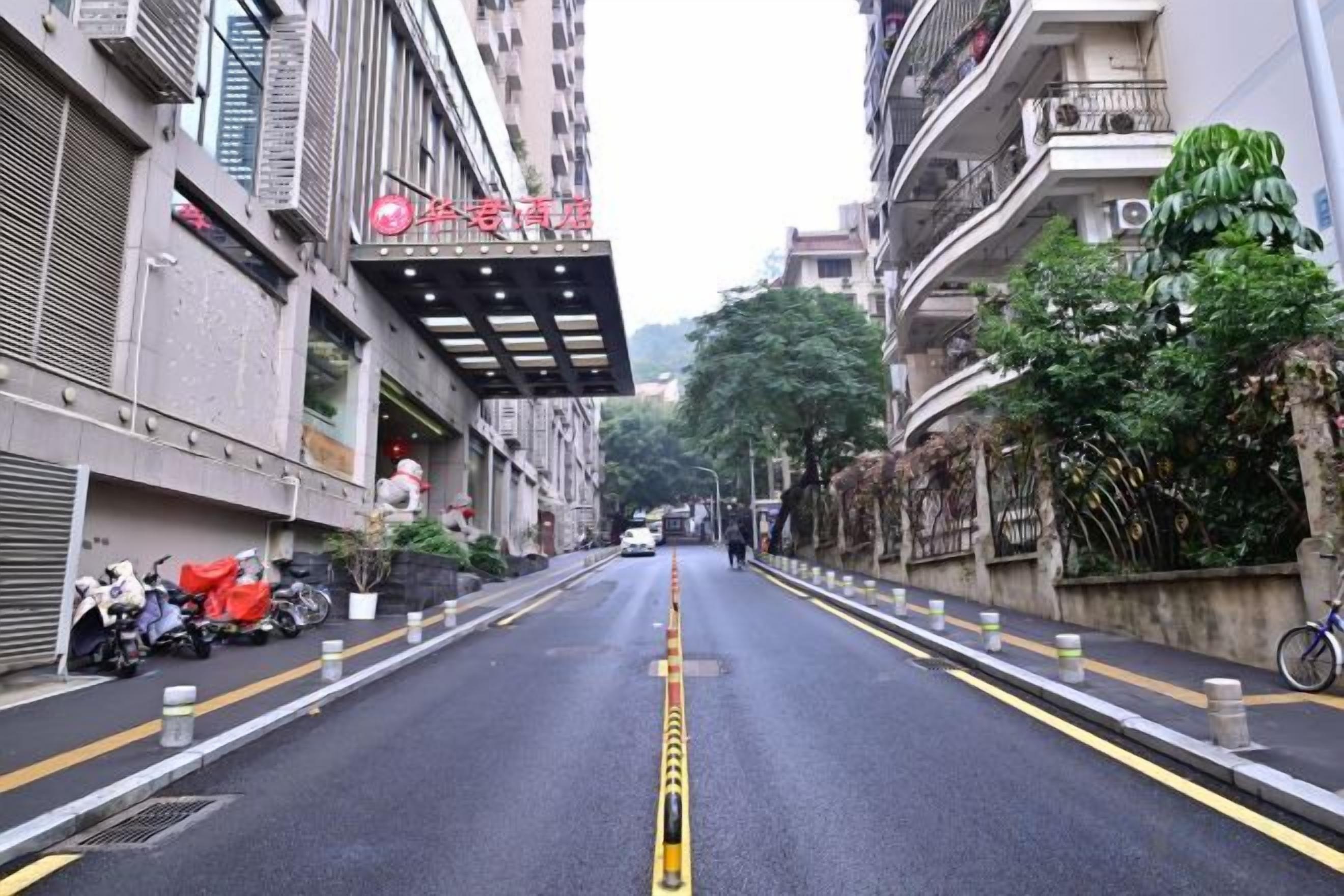 A street view with a building featuring a red sign, a clear road with yellow lines, and a parked bicycle on the right.