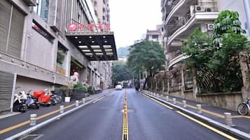 A street view with a building featuring a red sign, a clear road with yellow lines, and a parked bicycle on the right.