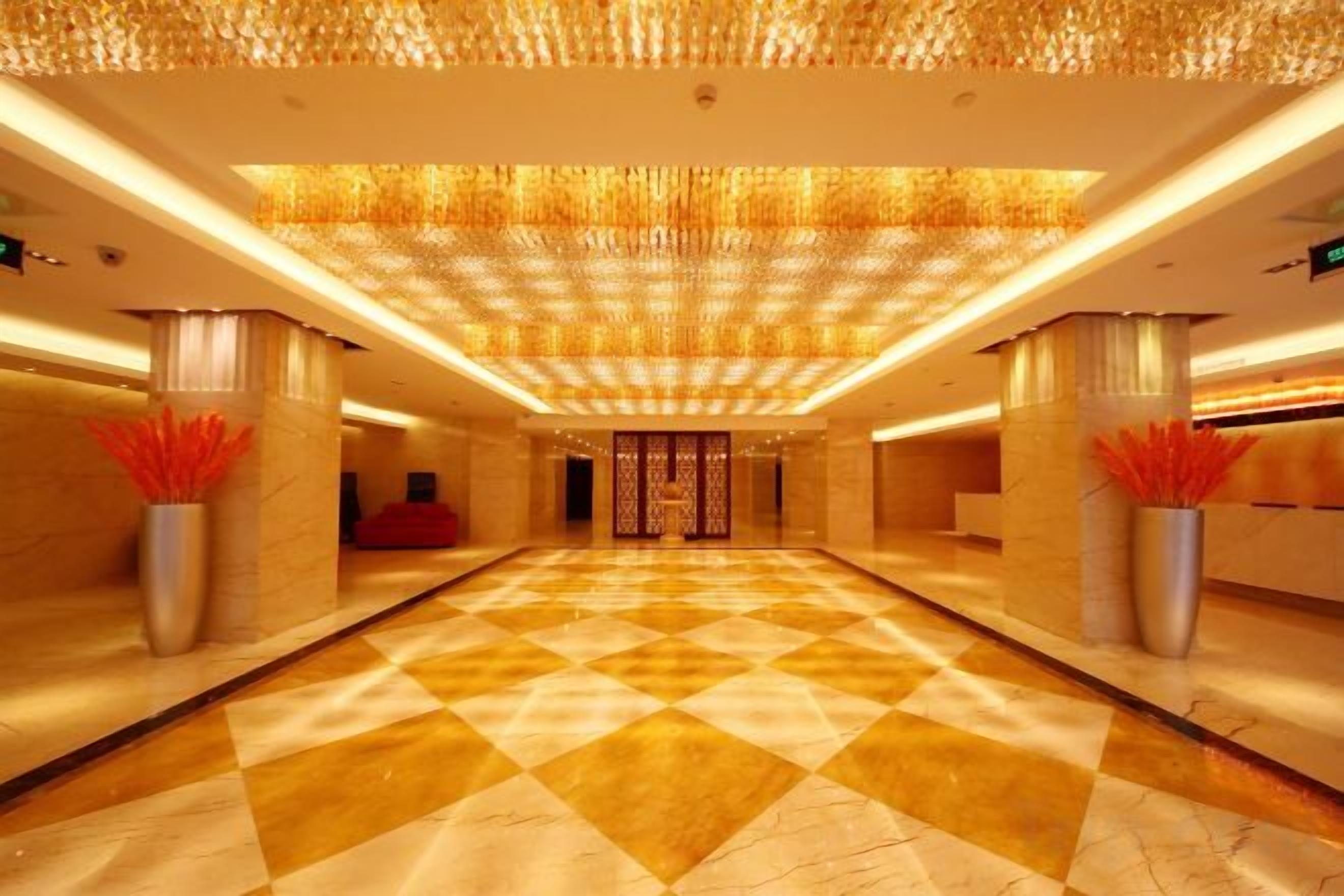 A spacious lobby with a checkered floor, large columns, and a decorative ceiling.