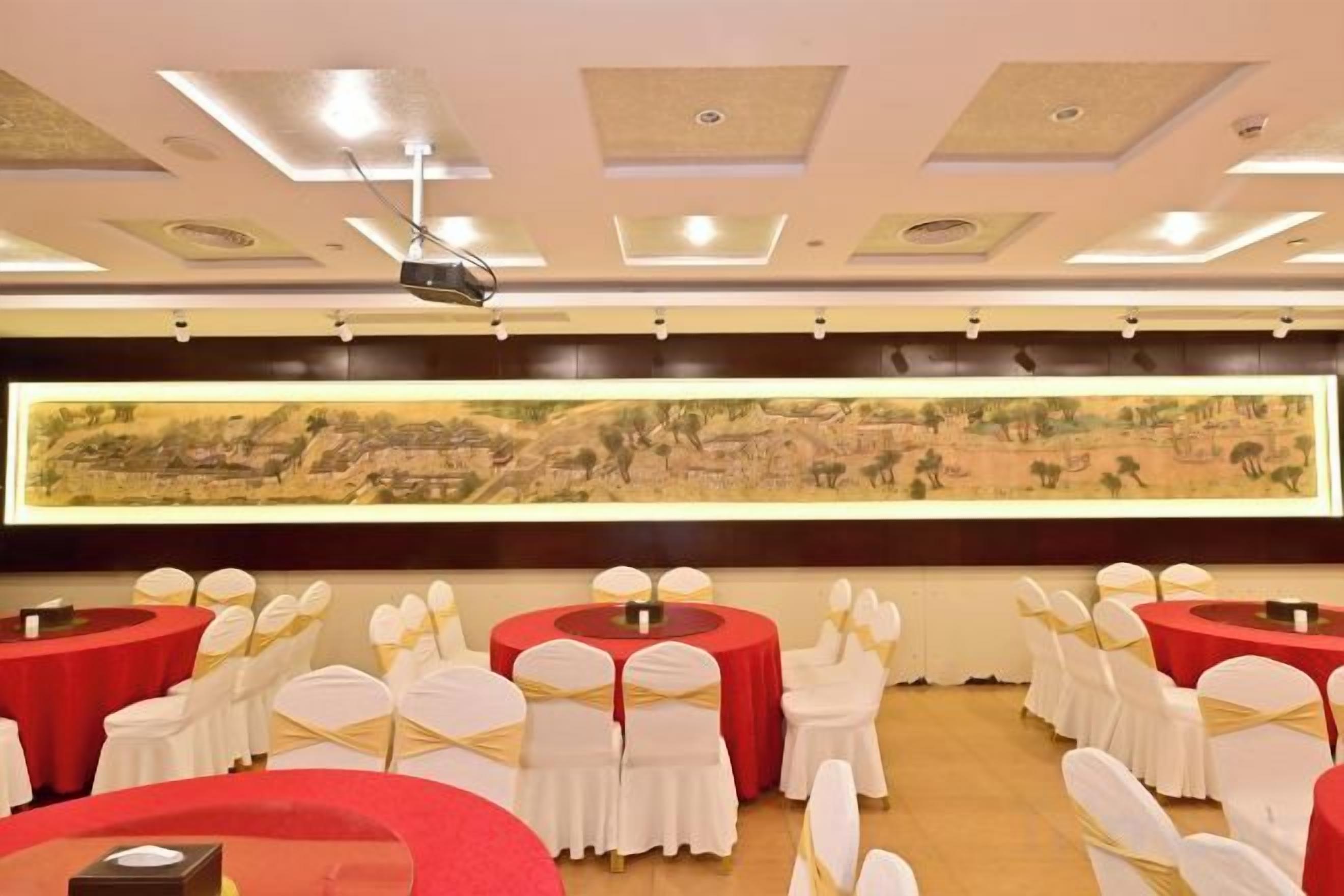 Un salón de conferencias con mesas redondas, sillas blancas y un cuadro grande colgado en la pared.