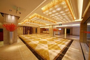A spacious lobby with a checkered floor, a reception desk, and a large decorative chandelier. - Huajun Hotel (Xiamen)