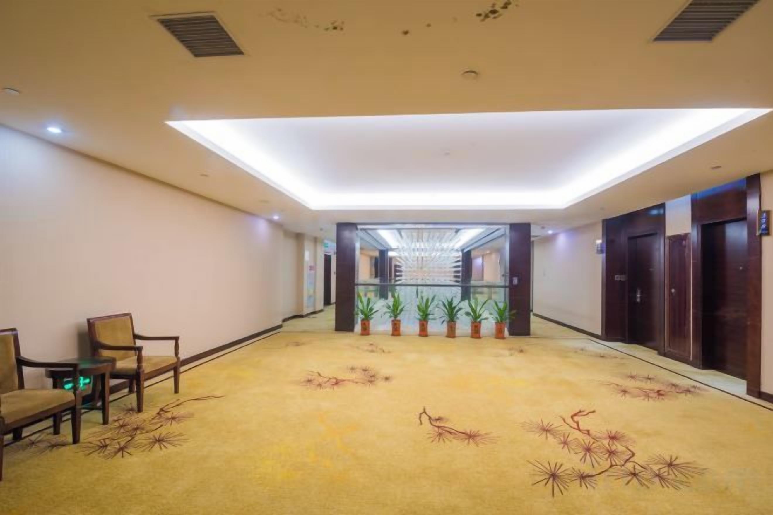 A hotel lobby with a long corridor, wooden doors, and a carpet with a floral pattern.