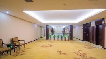 A hotel lobby with a long corridor, wooden doors, and a carpet with a floral pattern.