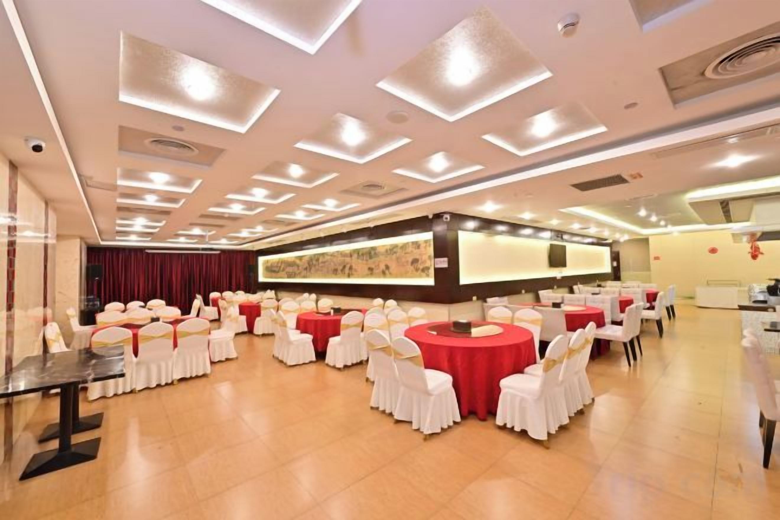 Un salón de banquetes con mesas redondas y sillas, un escenario y una barra larga.