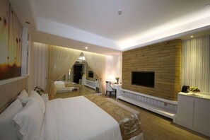 A hotel room with a large bed, a desk, a TV mounted on a wooden wall, and a mirror. - Huajun Hotel (Xiamen)