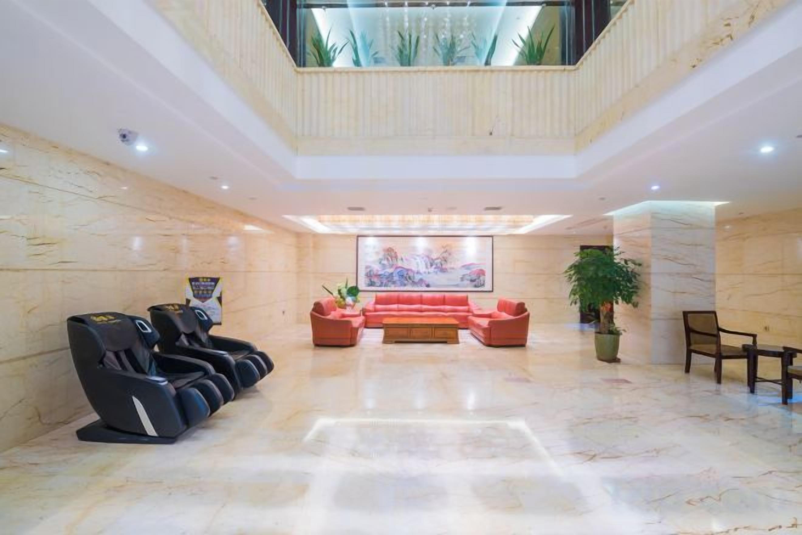 A lobby with a reception desk, massage chairs, a red sofa, and a large painting.