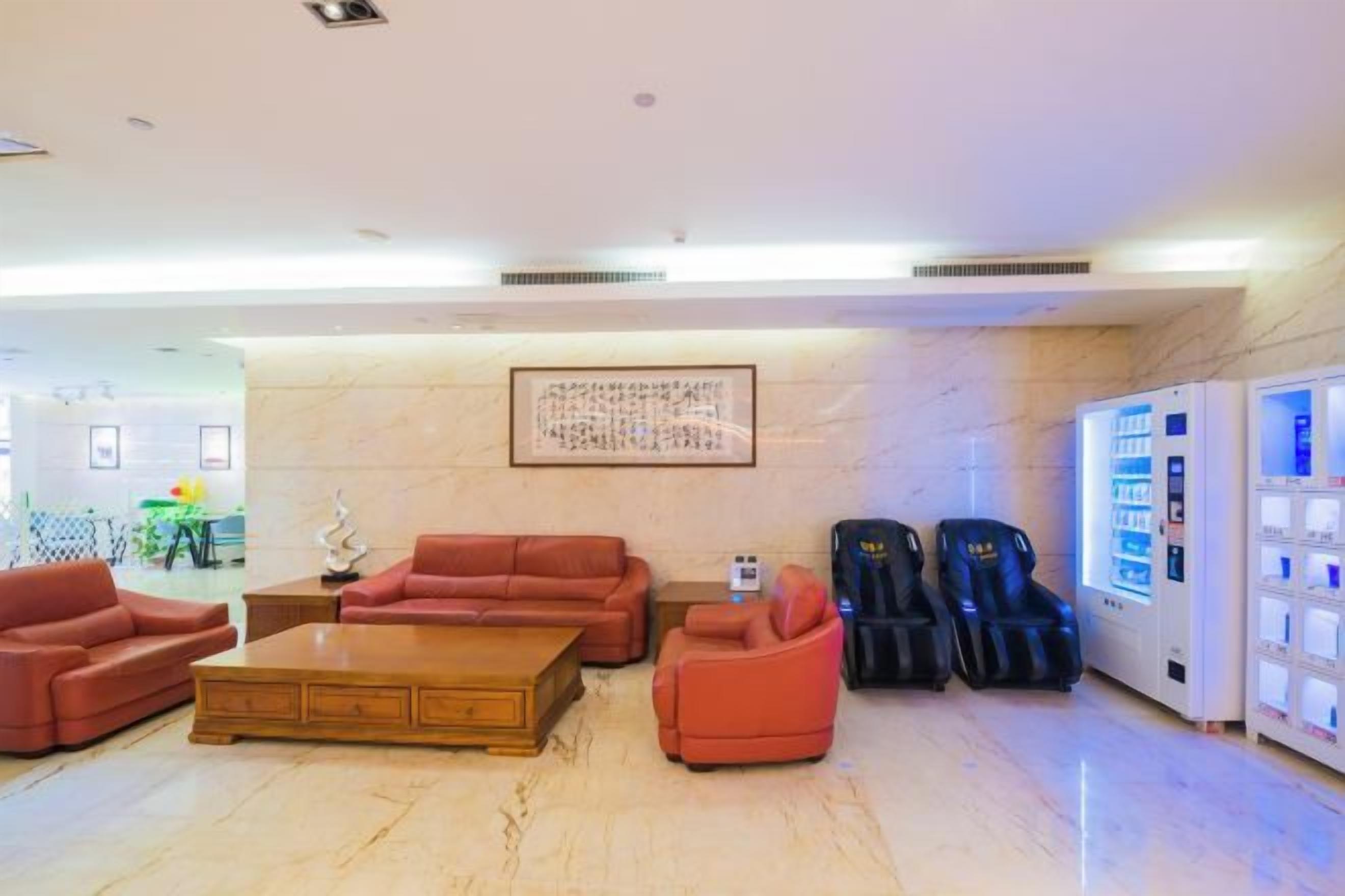 A lobby with leather sofas, a coffee table, massage chairs, and a vending machine.