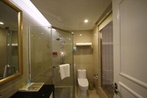 A modern bathroom with a glass shower enclosure, a toilet, and a sink with a mirror. - Huajun Hotel (Xiamen)