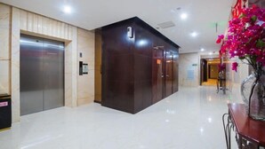 A modern elevator area with a marble floor and a dark elevator door. - Huajun Hotel (Xiamen)