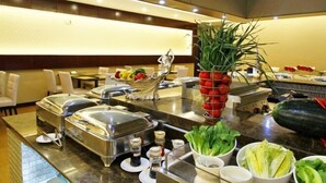 A buffet setup with various food items and condiments. - Huajun Hotel (Xiamen)