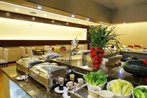 A buffet setup with various food items and condiments. - Huajun Hotel (Xiamen)