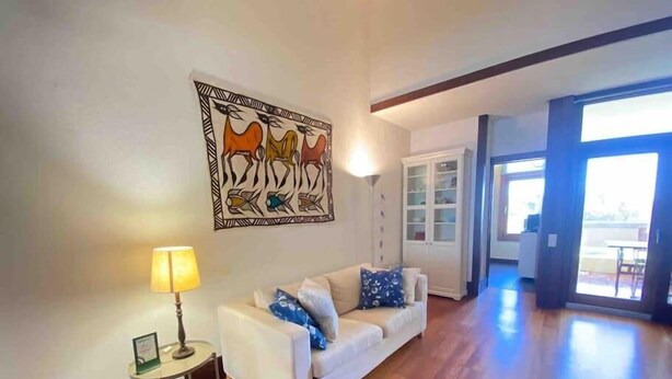 Una sala de estar con un sofá blanco, una lámpara y una obra de arte en la pared.