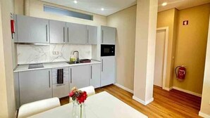 Une cuisine moderne avec des meubles blancs, un plan de travail en marbre et un micro-ondes encastré. On y trouve une table à manger avec des chaises et un vase de fleurs.