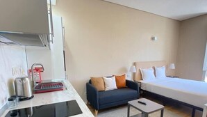 A hotel room with a bed, a sofa, a small table, a kitchenette with a stove and sink, and a mirror. - Setúbal Prime III (Setúbal)