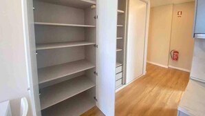 A room with a wooden floor, a white door, and a closet with multiple shelves. - Setúbal Prime III (Setúbal)