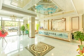 A hotel reception area with a reception desk, a large window, and a decorative ceiling. - Fengcheng Business Hotel (Haikou Fengxiang Road) (Haikou)