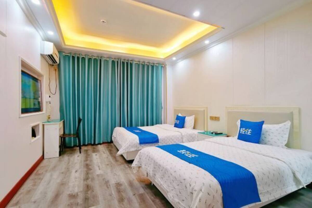 A hotel room with two beds, a desk, and a chair.
