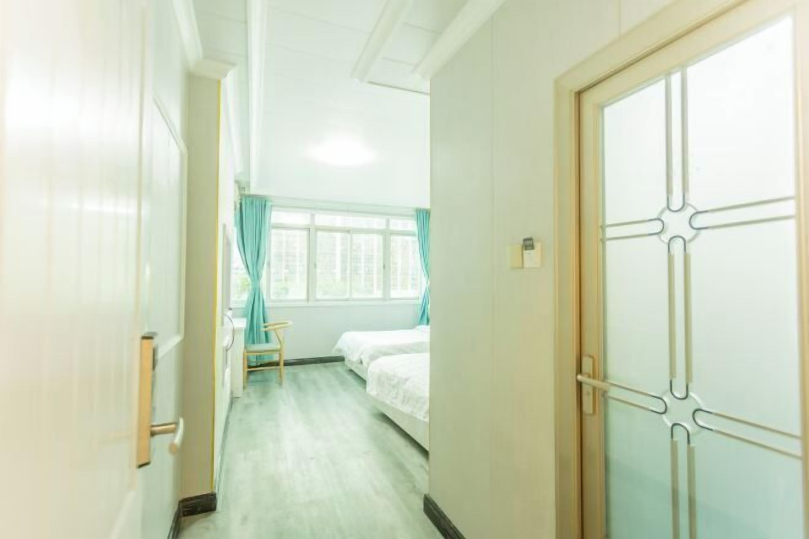A hotel room with a bed, a small table, and a window with curtains.