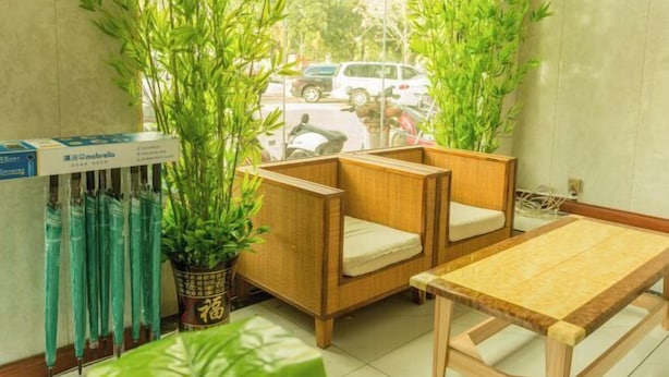 Una habitación con una mesa de madera y dos sillas, una planta en maceta y una ventana con vistas a la calle.