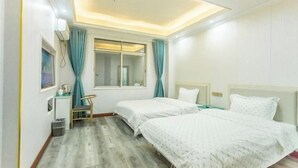 Habitación de hotel con dos camas, un escritorio, una silla, una ventana con cortinas y una lámpara en el techo.