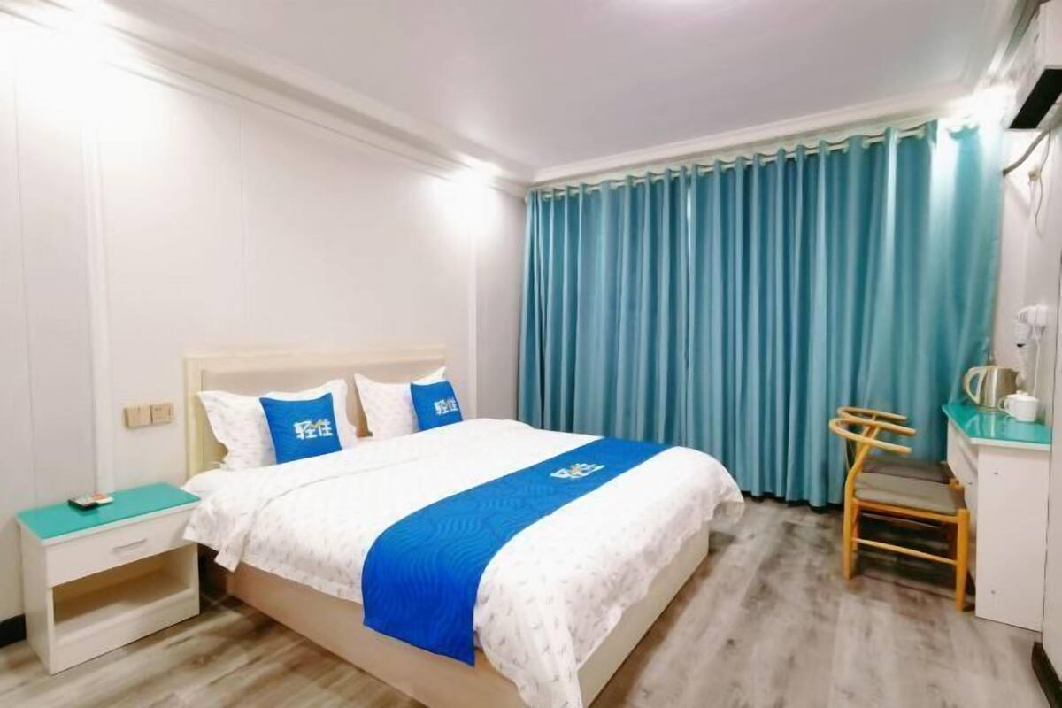 A hotel room with a bed, a nightstand, a desk, and a chair.