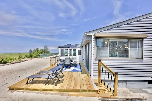 Relax on the spacious deck with ocean views, featuring a seating area and covered outdoor space with a table and chairs.