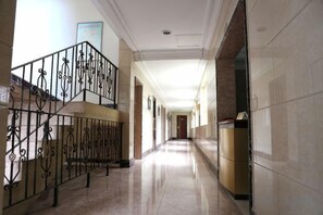 A hallway with a staircase, a door at the end, and a wall-mounted sign. - Jing Chuan Hotel (Jing County)