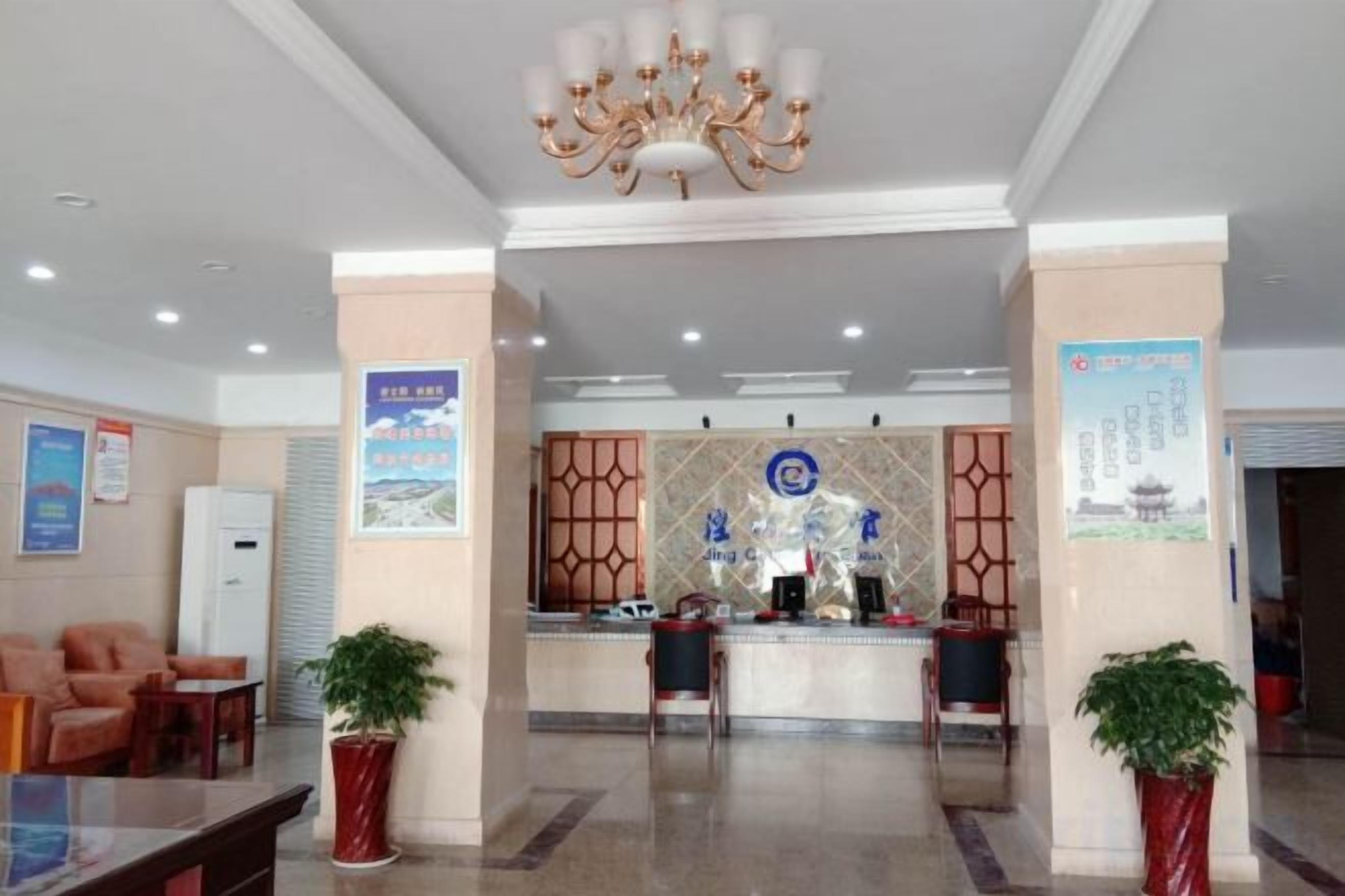 Un vestíbulo de hotel con mostrador de recepción, zona de estar y plantas decorativas.