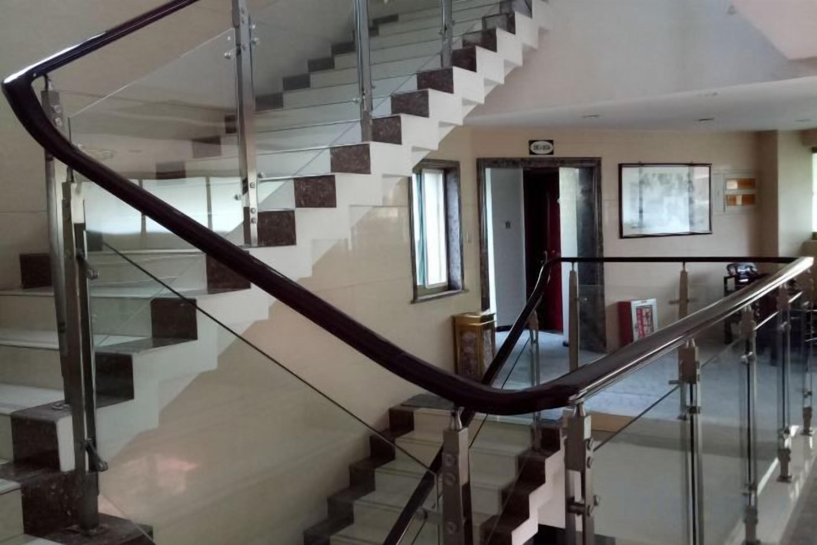 A modern interior with a glass staircase and a red door.