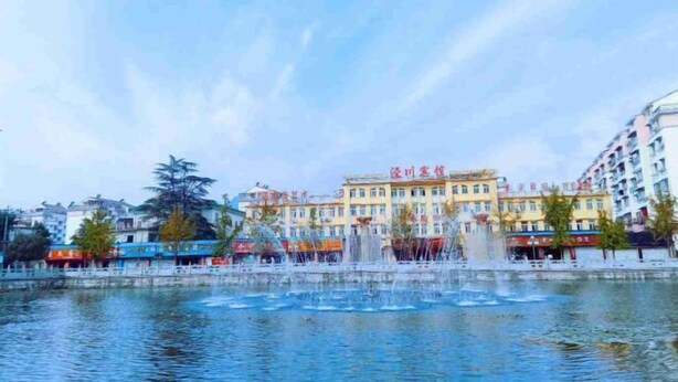 A waterfront area with a fountain, buildings, and a clear sky.