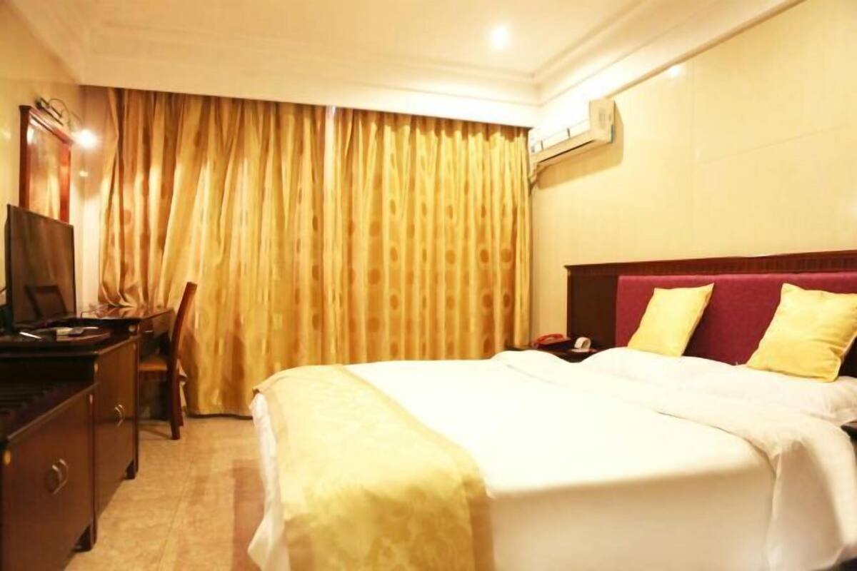 A hotel room with a bed, a desk, a chair, and a television.