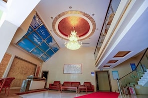 A hotel lobby with a reception desk, seating area, and a chandelier. - Jing Chuan Hotel (Jing County)