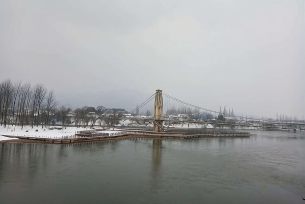 A large suspension bridge over a body of water with snow on the ground.