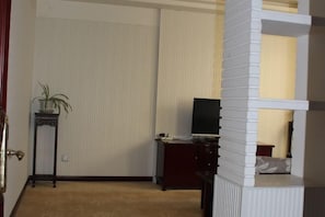 Una habitación con una cama, un escritorio, un televisor y una planta en maceta.