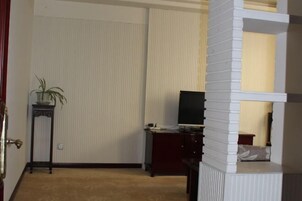 Una habitación con una cama, un escritorio, un televisor y una planta en maceta.