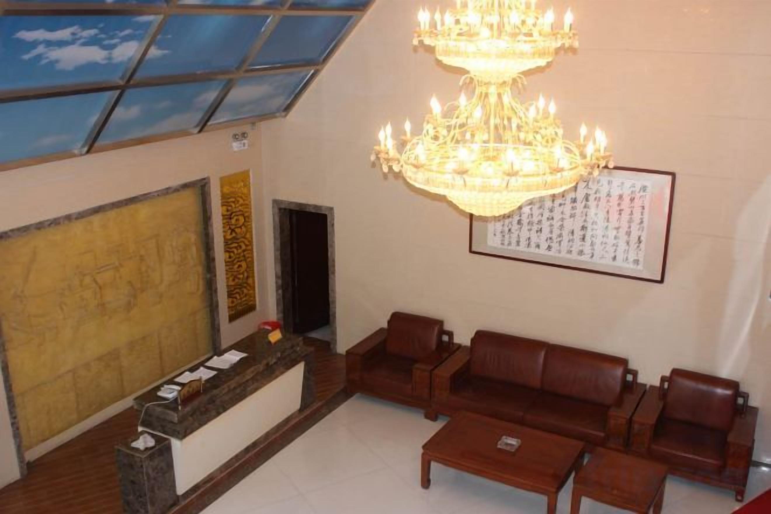 Un hall con mostrador de recepción, zona de estar, candelabro, obras de arte y un menú enmarcado.