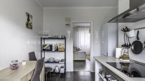 A modern kitchen with a dining area, featuring a built-in oven, a microwave, and a shelf with kitchen utensils. - Cosy and Bright in La Arena Beach (Zierbena)