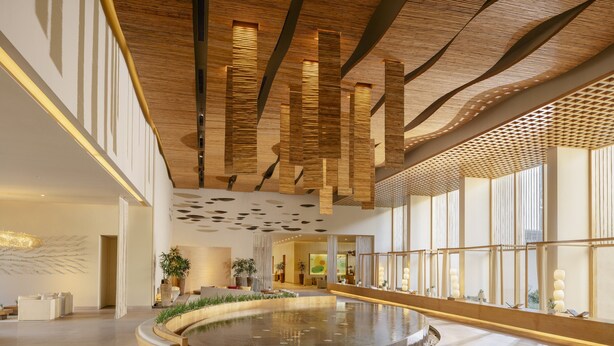 A spacious lobby with a central water feature, wooden ceiling panels, and large windows. - Six Senses Vana - A Wellness Retreat (Dehradun)